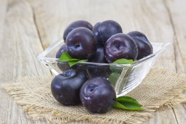 Tahta arka planda bir kasede taze erikler.