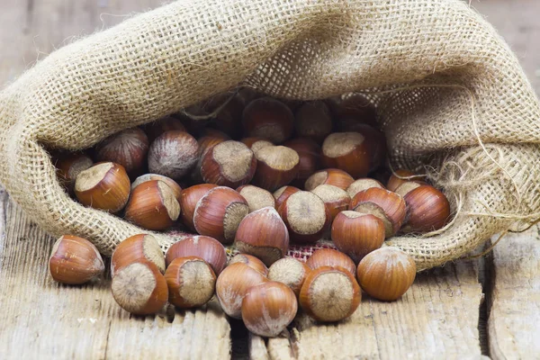 Avelãs em uma bolsa no velho fundo de madeira — Fotografia de Stock