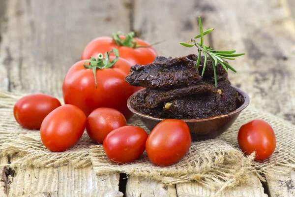 Ferske og tørkede tomater på trebakgrunn – stockfoto