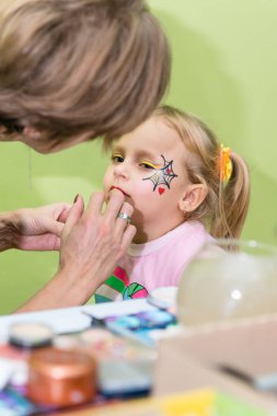 Makyaj sanatçısı Cadılar Bayramı partisine kız makyaj uygulamak.