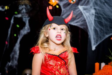 Bir çocuk, bir süpürge bir cadı şeklinde küçük bir kız örümcek ağları, kabak ve sonbahar yaprakları toplayan fonunda bir Cadılar Bayramı tatil pozlar..