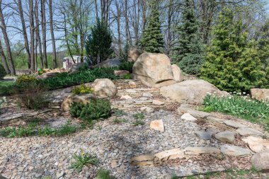 Taştan yapılmış Alp tepesi, nergisler, laleler, ladin ve ardıç ağacı parktaki sokağı süslüyor..