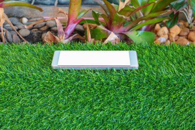 Yapay çimen yeşil arka plan üstünde hareket eden telefon