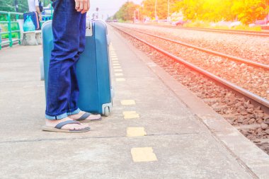 seyahat bacak erkek kot pantolon stand koymak ve bavul bekleyin tren istasyonu trail platformunun günbatımı ışık ve kopya alanı ile