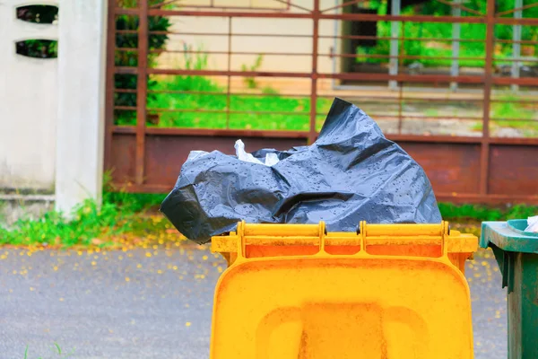 Bag black garbage in Yellow trashcan in the city with copy space — Stock Photo, Image