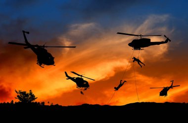 Siluet asker helikopter gün batımı ile saldırı aşağı iple inmek
