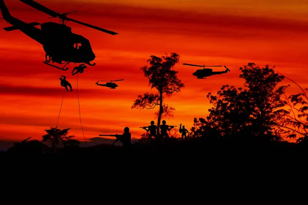 Silhouette Soldaten abseilen, um aus dem Hubschrauber anzugreifen mit Krieger Vorsicht Gefahr am Boden Sonnenuntergang Hintergrund verschwimmen und kopieren Raum hinzufügen Text (Konzept Feindseligkeiten beenden, um den Frieden) — Stockbild Soldaten seilen sich vom Hubschrauber ab, um anzugreifen — Stockfoto