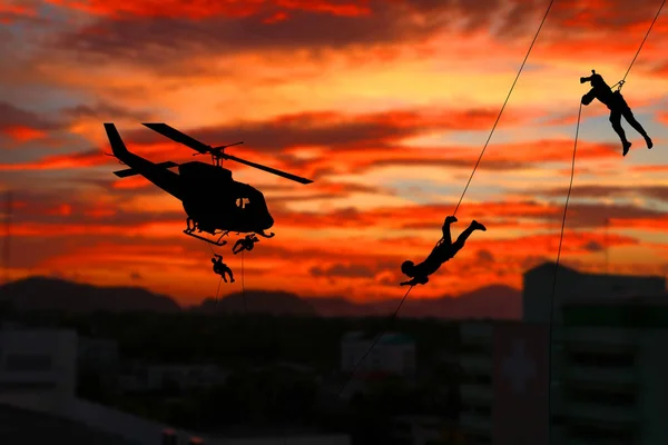 Silhouette Soldiers rappel down to attack from helicopter
