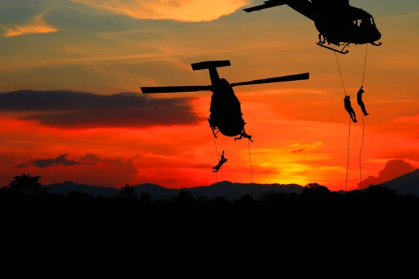 Soldados silueta rappel abajo para atacar desde el helicóptero con puesta de sol — Foto de Stock