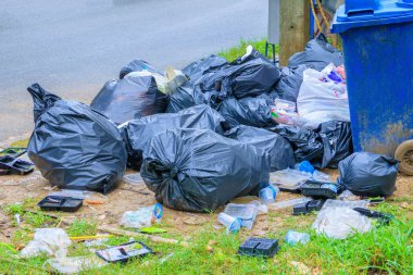 Siyah çöp yol kenarında ve yağmur damlaları çanta üzerinde kazık 
