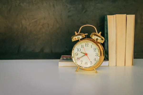 Reloj despertador viejo vintage oro y libro sobre blanco sobre negro —  Fotos de Stock