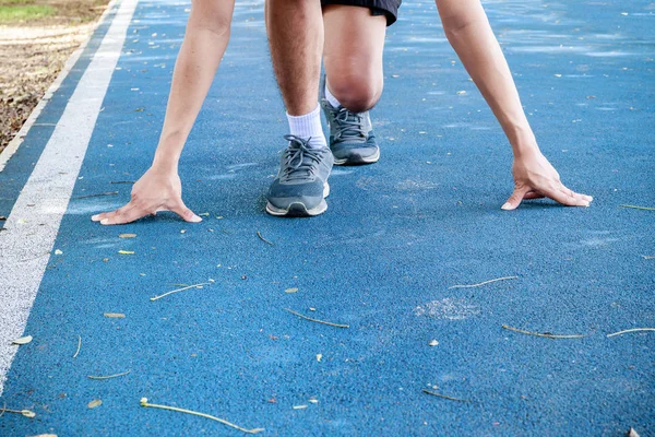 Bras mâle toucher plancher commencer pose formation en cours d'exécution sur la piste en caoutchouc — Photo