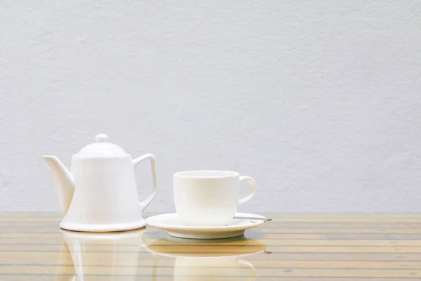 Taza de café y tetera blanca En la mesa de vidrio fondo de pared de madera y cemento —  Fotos de Stock