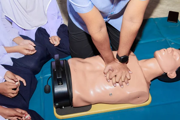 Cprの医学のダミーが付いている手の学生の心臓ポンプ、緊急リフレッシャーの訓練で — ストック写真