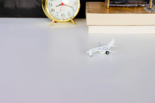 Avión de plástico avión juguete pasajero sobre fondo blanco. reloj despertador borroso oro viejo y libro — Foto de Stock