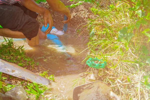 broken pipe in hole with water motion at roadside and plumber