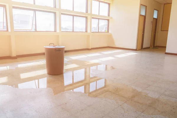 water leak drop interior office building in red bucket from Ceiling and flow on terrazzo floor