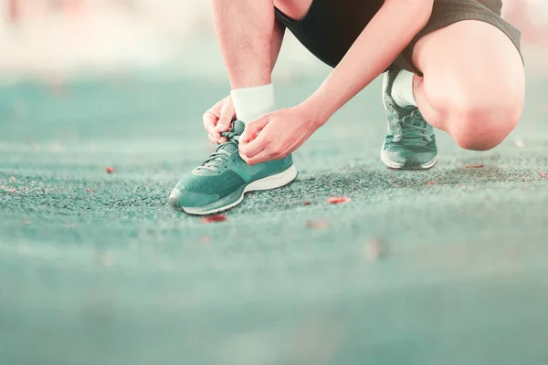 young male runner tying shoelaces old in runner exercise for  health lose weight concept on track rubber