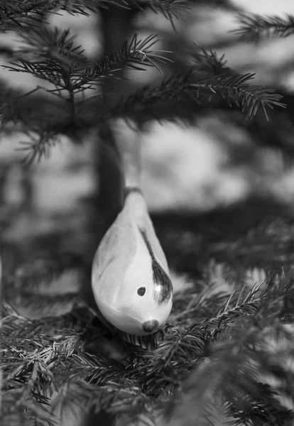 christmas decoration in the shape of a bird on the twig of christmas tree in black and white