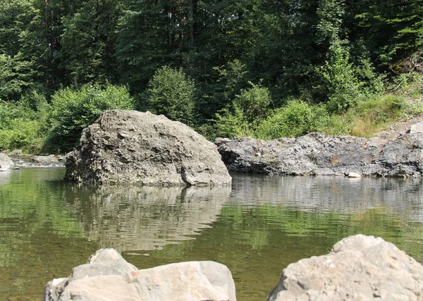 big rock in the river reflecting on the water surface, Moravka river, Czech Republic