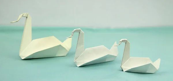 three origami paper swans of various sizes in the line