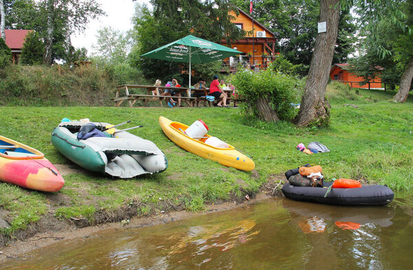 rafts and canoes parked on the bank and paddlers relaxing on Sazava river, Czech Republic