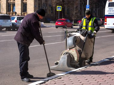 Voronej, Rusya - 27 Nisan 2017: Janitors yolun kaldırımından çöpü temizliyor