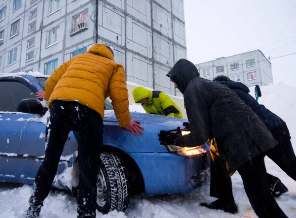 Murmansk, Rusya - 22 Ocak 2017: İnsanlar karda mahsur kalmış bir araba dan dışarı itiyor