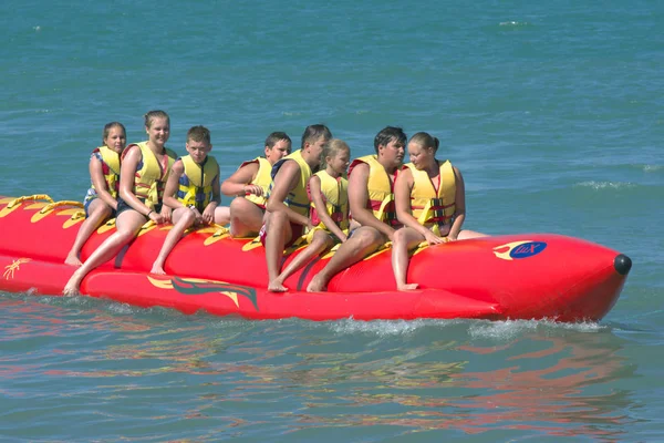 stock image Sochi, Russia - June 24, 2014, People ride on an inflatable raft in the shape of a banana