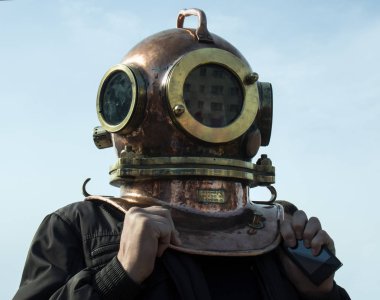 Man stands in his head to put on an old diving helmet clipart