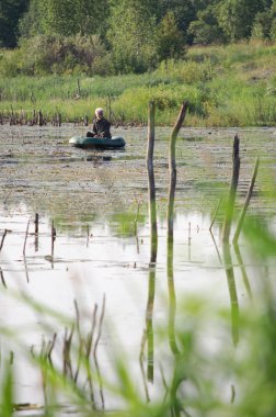 Vyazma, Rusya - 19 Temmuz 2011: Orta Rusya'da bir gölüzerinde bir lastik tekne bir balıkçı