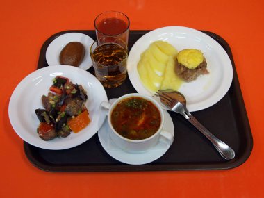 Yemek odasında ki masada öğle yemeği ile kırmızı bir tepsi var.