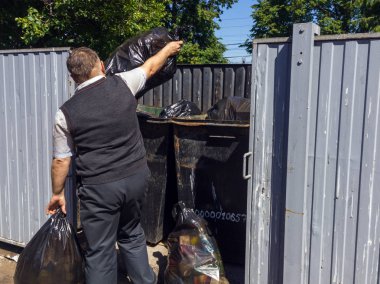 Lipetsk, Rusya - 10 Haziran 2018: Bir adam plastik poşetleri çöple bir konteynere atıyor