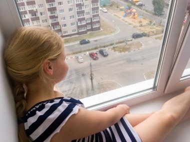 Voronej, Rusya - Juny 29, 2018: Bir kız pencere nin üzerinde oturur ve bahçeye bakar