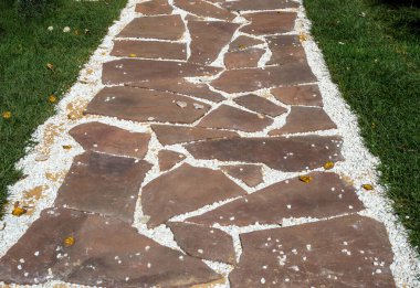 Beton kiremitler ve çakıl parçalarıyla bir bahçe yolu süslemesi