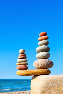 Mavi gökyüzü ve yaz denizinin arka planında iki renkli dengeli kaya piramidi. Denge, uyum ve meditasyon kavramı