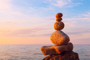 Uyum ve denge kavramı. Gün batımında Rock Zen. Denize karşı denge ve denge taşları