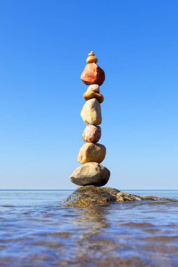 Kaya Zen piramidi rengarenk çakıl taşları denizin arka planında suyun üzerinde duruyordu. Denge, uyum ve meditasyon kavramı