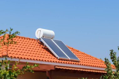 Solar su ısıtma paneli ve su toplayıcısı bir evin çatısında.