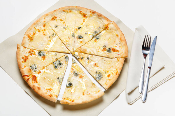Pizza with chicken and broccoli on a white plate and on a white background, knife and fork on a napkin. top view