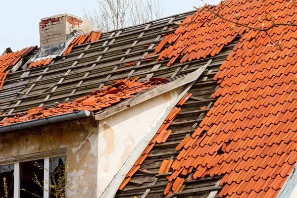 the roof of the old house with a damaged coating of red ceramic tiles