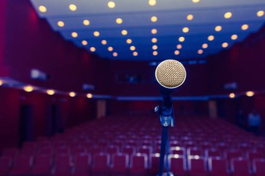 Karanlık bir salonun arka planında seyirciler için oturma izni olan bir mikrofon. Seyirciler için sandalyeler