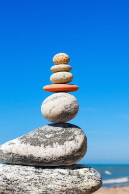 Taşlar mavi gökyüzü ve yaz denizi üzerinde dengelenir. Denge ve uyum kavramı