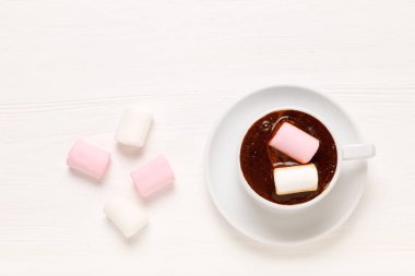 Beyaz kupa, kahve, beyaz ve pembe lokum ve ahşap masa. Üst görünüm