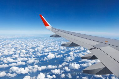 Uçağın kanatları Cumulus bulutlarının üzerinde uçuyor.