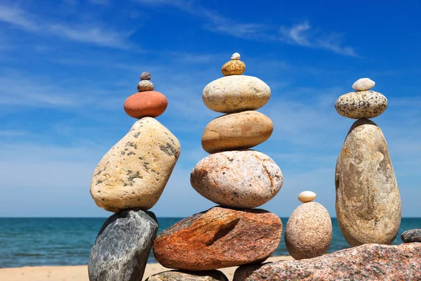 几座岩石成堆的彩色卵石金字塔坐落在海滨的背景上 和谐和冥想的概念 — 图库照片