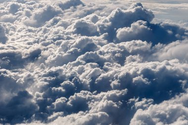 Büyük, beyaz kümülonimbus bulutları ve mavi gökyüzü. Uçak penceresinden görüntüle
