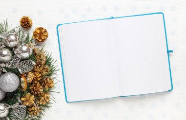 Beyaz arka planda Noel çelengi ve Blank açık not defteri. Yeni yıl hedefleri konsepti, modelleme, üst görünüm, kopyalama alanı