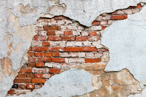 old wall with crumbling plaster and visible masonry of red bricks