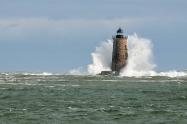 Giant waves cover the stone tower of Whaleback lighthouse in southern Maine during an astronomically high tide. clipart